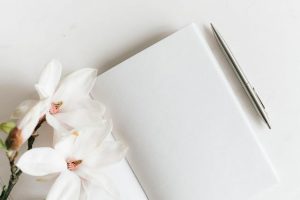 photo of a blank sketchbook with white flowers laying on top
